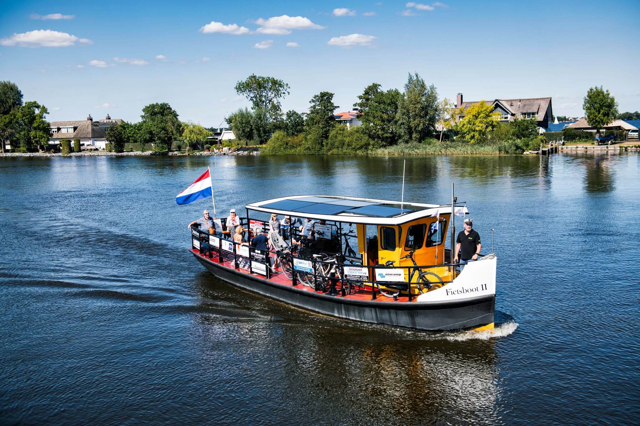 Boot mit PV-Anlage auf dem Dach fährt auf einem See.