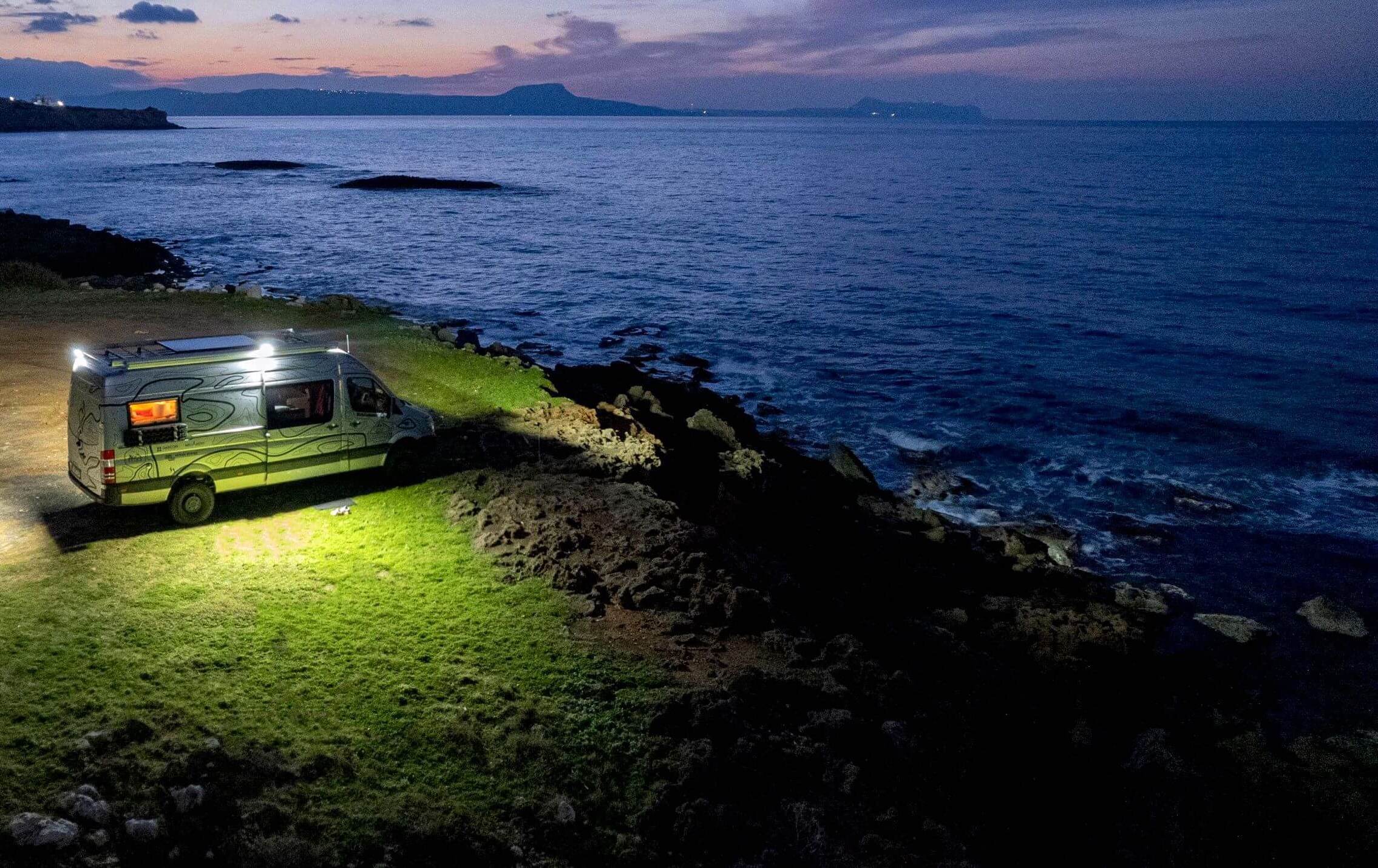 Wohnmobil parkt an einer Küste bei Sonnenuntergang