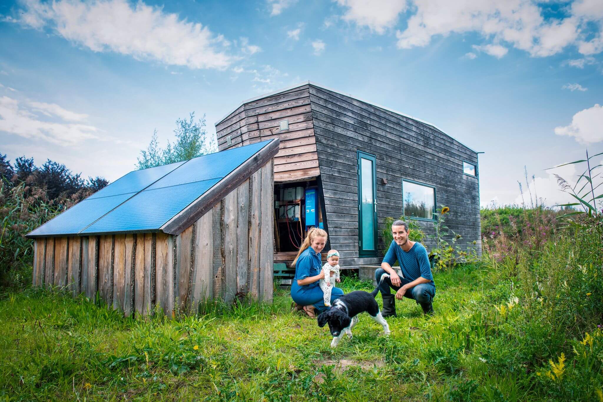 Familie mit kleinem Kind vor einem energieautarken Tiny House.